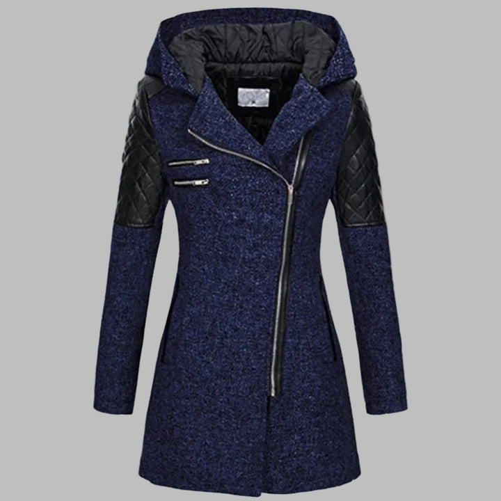 Blauwe dames winterjas met capuchon, asymmetrische rits en gewatteerde zwarte schouderstukken. Stijlvolle en warme jas voor koude dagen.